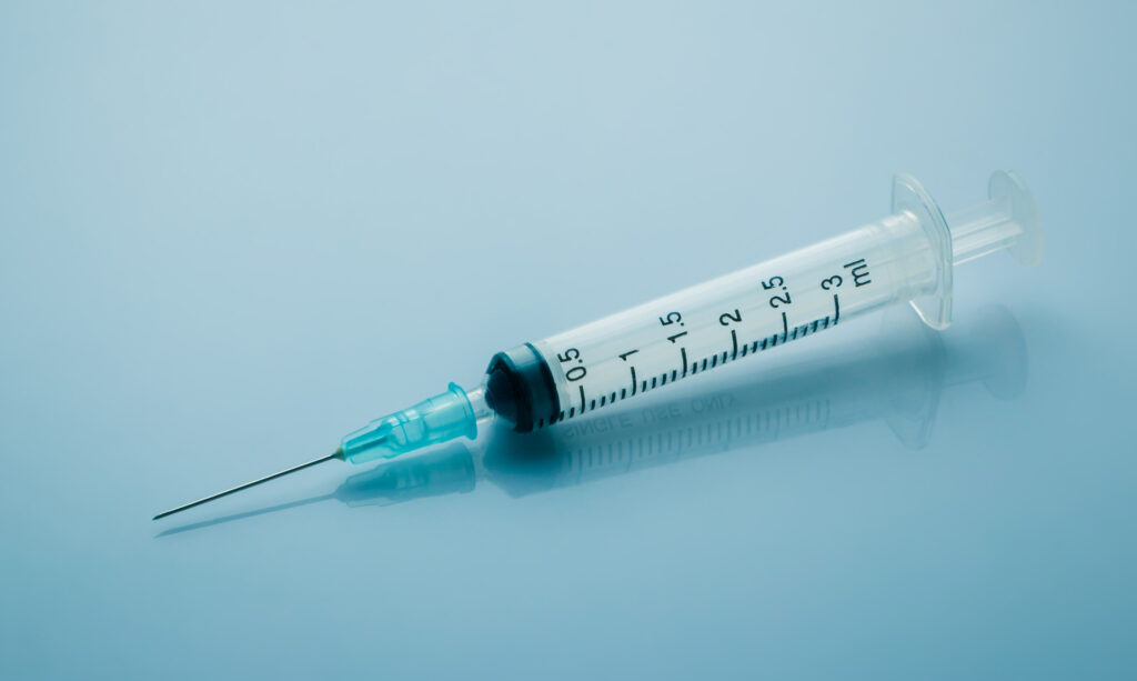 A close-up image of a 3ml plastic syringe with a fine needle attached, placed on a smooth, reflective blue surface. The syringe is empty and positioned horizontally with clear measurement markings visible along the barrel. The image has a clinical and sterile feel, commonly associated with medical or aesthetic treatments.